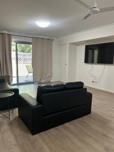 a living room with a black couch and a tv at Stay at Bambas in Kingston