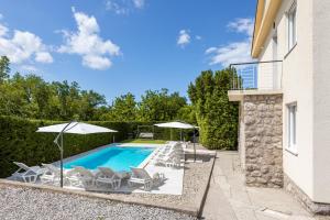 a swimming pool with chairs and umbrellas next to a building at Villa Joy in Jadranovo