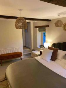 Schlafzimmer mit einem Bett, einer Bank und einem Tisch in der Unterkunft Boho Chic Cottage & Wild Garden nr Soho Farmhouse in Steeple Aston