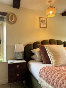 ein Schlafzimmer mit einem Bett und einer Lampe auf einem Tisch in der Unterkunft Boho Chic Cottage & Wild Garden nr Soho Farmhouse in Steeple Aston + 45 Fotos