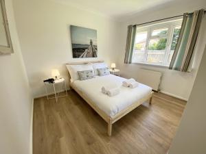 a bedroom with a bed with white sheets and a window at Daisy Cottage in Lymington