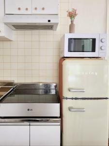 a microwave on top of an old refrigerator in a kitchen at Cozy Moon Ok Stay in Seoul in Seoul +13 photos