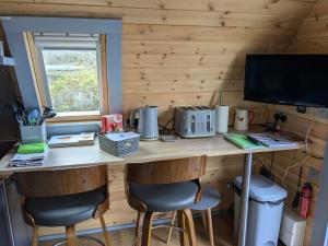 a desk in a room with two chairs and a television at Robins Nest Pod in Breakish +14 photos