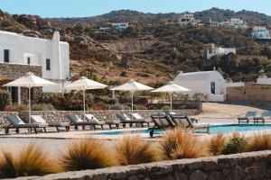 a group of chairs and umbrellas next to a pool at Archon Seaside Retreat in Plaka