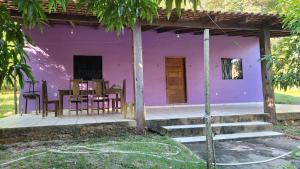 a purple house with a table and chairs on a porch at Casa de Praia Pindobal in Santarém