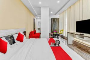 ein Schlafzimmer mit einem weißen Bett mit roten Kissen und einem Fernseher in der Unterkunft Lutino Homes Ramurthynagar main Road opposite D Mart in Bangalore