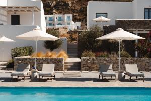 a group of chairs and umbrellas next to a pool at Archon Seaside Retreat in Plaka