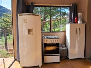 a kitchen with a stove and a refrigerator and a window at Chale2RabodeGalo in Santana do Riacho