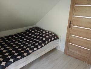 a small bed with a black and white checkered sheet at Skalny domek in Krościenko
