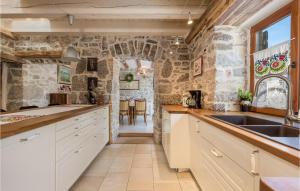 a kitchen with white cabinets and a stone wall at 3 Bedroom Beautiful Home In Ruzici in Ružići