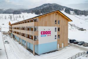 a building with a google sign on it in the snow at COOEE alpin Hotel Bad Kleinkirchheim in Bad Kleinkirchheim