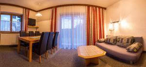 ein Wohnzimmer mit einem Tisch und einem Sofa sowie ein Esszimmer in der Unterkunft Pension Schweizerhof in Waidring