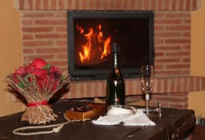 a bottle of wine on a table in front of a fireplace at Casa Rural Las Albertas in Arbancón