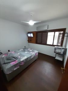 Un dormitorio con una cama en una habitación con ventanas. en Casa Ampla 2 dormitorios LARANJAL temporada, en Pelotas