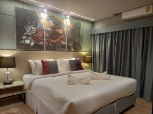 a bedroom with a large white bed with a painting on the wall at AD resort ชะอำ in Ban Bo Khaem +49 photos