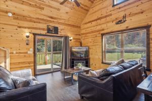 ein Wohnzimmer mit Sofas und einem TV in einer Hütte in der Unterkunft 10 minutes to Parkway, BunkBeds, Hot Tub, Firepit - Hidden Bear in Starkeytown