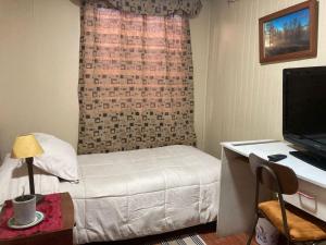a bedroom with a bed and a desk with a television at Hostal Sol Temuco in Temuco