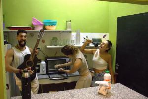 a group of people standing in a kitchen with a guitar at Parla Hostel in Buenos Aires