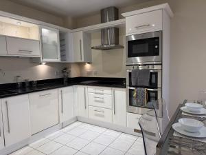 Una cocina blanca con gabinetes blancos y una mesa. en Two Bed Flat In Wimbledon, en Londres 21 fotos más