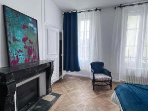 a living room with a fireplace and a chair at La Maison de Colette in Trie-Château