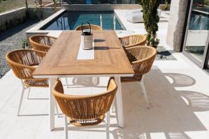 a wooden table with rattan chairs sitting next to a pool at Oasis Villa 6 in Khlorakas