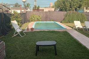 a small pool with chairs and a stool in a yard at Casa con pileta y 3 dormitorios in Funes