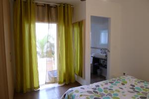 a bedroom with a bed and a window with yellow curtains at Casa Jamila in El Alquián +23 photos
