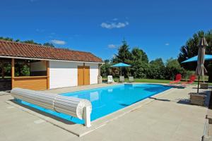 una piscina con banco y sombrillas en Saint roch 87, en Eyjeaux