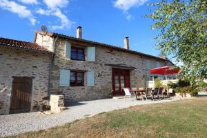 Una casa de piedra con una mesa y sillas delante de ella. en Saint roch 87, en Eyjeaux