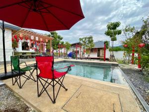two chairs and an umbrella next to a swimming pool at Taka Onzen in Ban Khao Ket