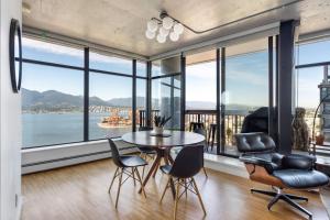 a dining room with a table and chairs and large windows at The W, Modernized 2 bedroom Downtown Highrise in Vancouver