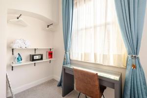 史云顿Stylish flat in central location with free parking的一张桌子,房间有一个窗口,有蓝色窗帘