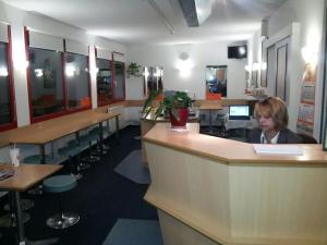 a woman sitting at a counter in a waiting room at Motel 24h Bremen in Bremen