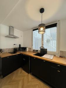 a kitchen with black cabinets and a large window at Petit appt cosy et moderne in Perpignan