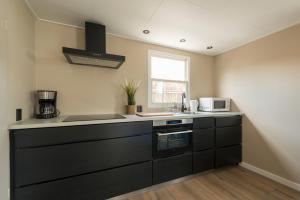 a kitchen with black cabinets and a sink and a window at 49, Efteling - Beekse Bergen - Dog Friendly in Oisterwijk +28 photos