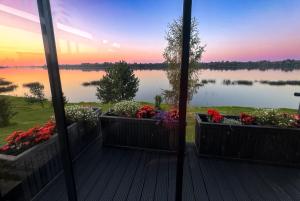 a view of a lake from a porch with flowers at Doles skati, kubls - iekļauts cenā in Salaspils +18 photos
