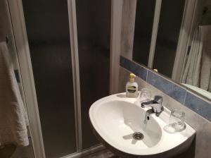 y baño con lavabo blanco y ducha. en Pensión Princesa, en Granada