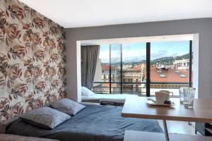 a bedroom with a bed and a table and a balcony at Le Grand Hôtel -Centre Croisette in Cannes