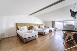 a large room with two beds and a television at Sé INN Studios by House and People in Braga