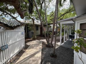 a house with a fence and a porch with trees at Ibis Suite - Southernmost Sanctuary in Key West +8 photos