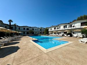 a swimming pool in a resort with chairs and tables at Villaggio Lido-Carraro Immobiliare Jesolo-Family Apartments in Cavallino-Treporti