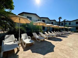 a row of white lounge chairs and umbrellas at Villaggio Lido-Carraro Immobiliare Jesolo-Family Apartments in Cavallino-Treporti