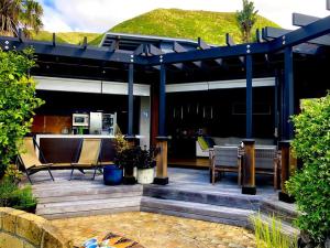 a house with a patio with a roof at Ahipara Beach Front, modern stylish bach in Ahipara