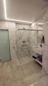Un baño con lavabo y ducha de cristal. en Vem Para o - Motel Marselha 2, en São Paulo