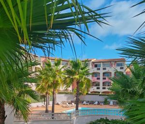 a view of the hotel from the palm trees at Résidence Agathéa - Centre Port - Cap d'Agde in Cap d'Agde