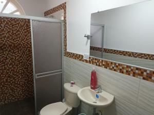 a bathroom with a toilet and a sink and a mirror at Hospedaje Casa Cultural Saberes in Neiva