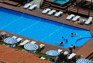 2 persone che nuotano in una piscina con ombrelloni di Hotel Tejas Rojas a Villa Gesell