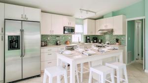 una cocina con armarios blancos y una isla blanca con taburetes en Tidewater Views by Last Key Realty, en Cudjoe Key 11 fotos más