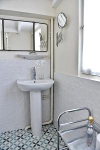 a white bathroom with a sink and a mirror at Maison Henri Chardon in Barfleur