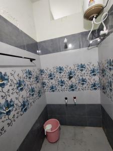 a bathroom with blue and white flowers on the wall at Buddhar Illam in Palni +4 photos